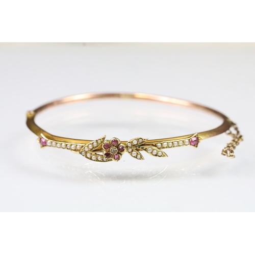 14 - Early 20th Century 9ct gold bangle bracelet having a ruby and pearl set floral spray to the front wi... 