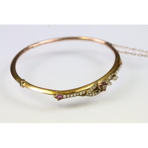 14 - Early 20th Century 9ct gold bangle bracelet having a ruby and pearl set floral spray to the front wi... 