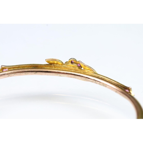 14 - Early 20th Century 9ct gold bangle bracelet having a ruby and pearl set floral spray to the front wi... 