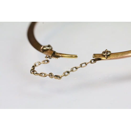 14 - Early 20th Century 9ct gold bangle bracelet having a ruby and pearl set floral spray to the front wi... 