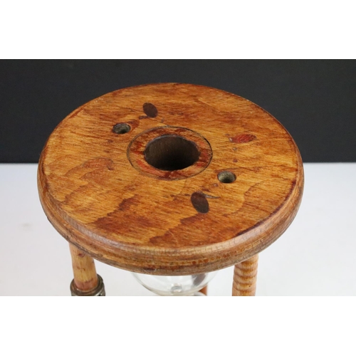 90 - Large glass egg timer, the frame formed from an old wooden weaving bobbin, 30cm high