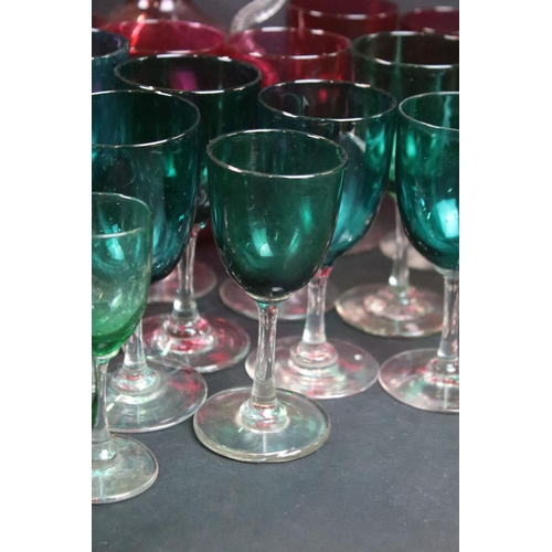 59 - Large selection of green (20) and cranberry (12) clear stemmed glasses with small pouring jugs and c... 