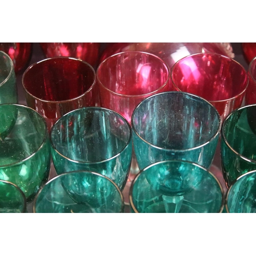 59 - Large selection of green (20) and cranberry (12) clear stemmed glasses with small pouring jugs and c... 