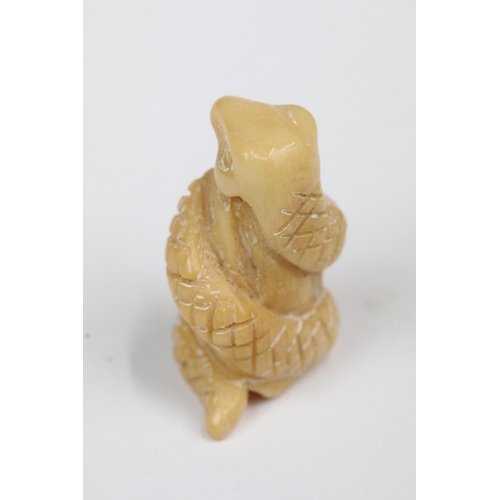 207 - Four carved bone miniature netsuke figures to incude signed dragons head, snake coiled around gold, ... 