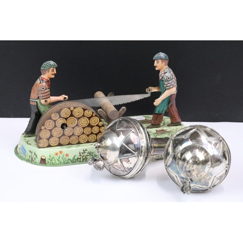 249 - A tin plate clockwork toy of wood workers together with a pair of silver plated rattles.