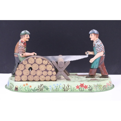 249 - A tin plate clockwork toy of wood workers together with a pair of silver plated rattles.