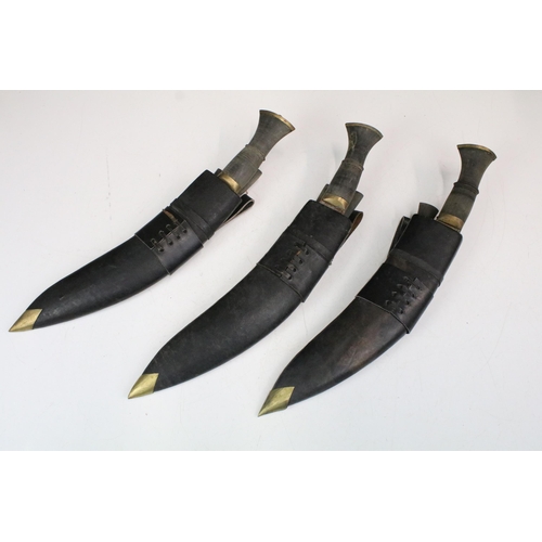 234 - A collection of three Kukri knives, all in leather scabbards and complete with tool / small knives.