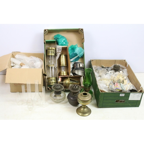 413 - Variety of oil lamp optics and white shades, together with an assortment of storm lanterns