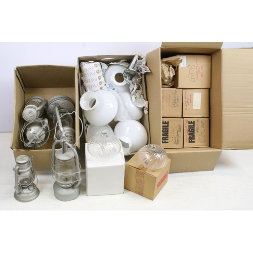 413 - Variety of oil lamp optics and white shades, together with an assortment of storm lanterns