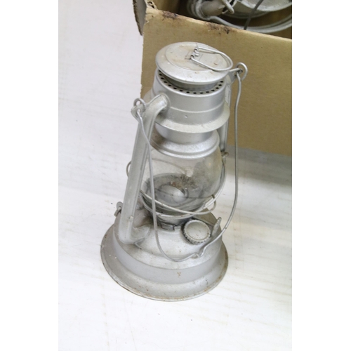 413 - Variety of oil lamp optics and white shades, together with an assortment of storm lanterns