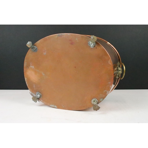 131 - Copper oval planter with rolled rim, brass lion mask drop ring handles and raised on four brass paw ... 