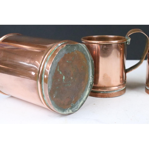 135 - Set of three copper graduating measuring tankards with loop handles, largest 14cm high