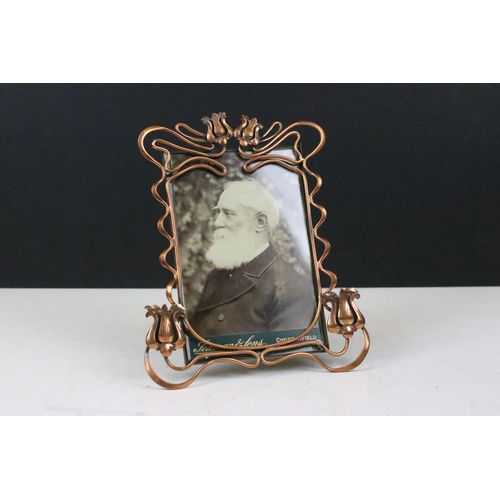 138 - Art Nouveau copper picture photograph frame with flower and ribbon detailed surround, having a stand... 