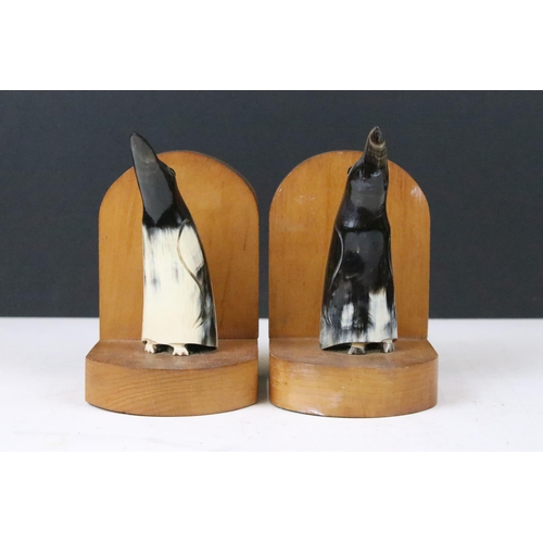 143 - Pair of Art Deco wooden bookends, each mounted with a horn penguin, 15cm high