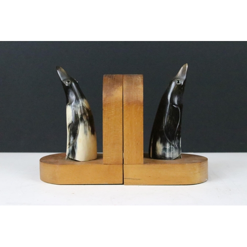 143 - Pair of Art Deco wooden bookends, each mounted with a horn penguin, 15cm high