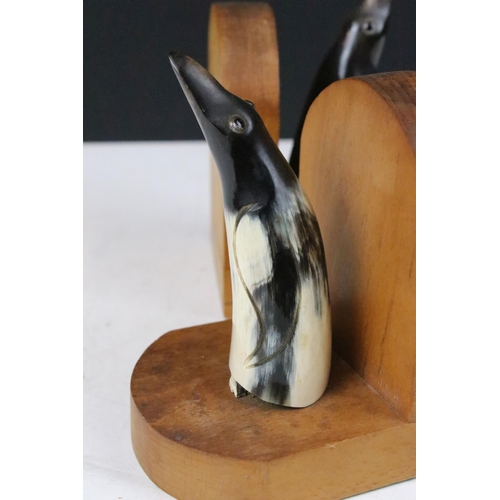 143 - Pair of Art Deco wooden bookends, each mounted with a horn penguin, 15cm high