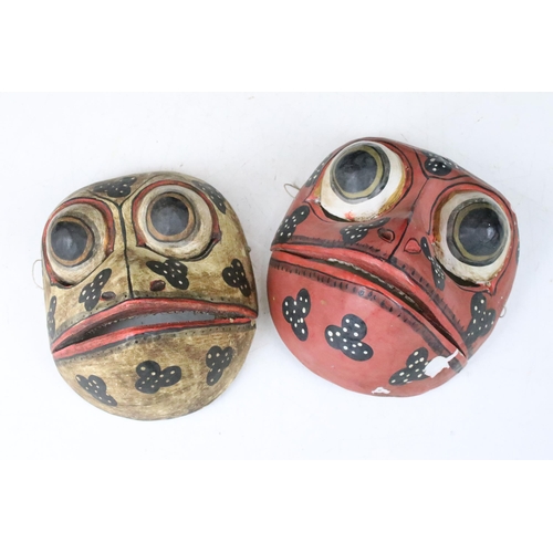 148 - Two mid 20th century folk art tribal wooden hand painted frog masks with articulated jaws, H 17cm