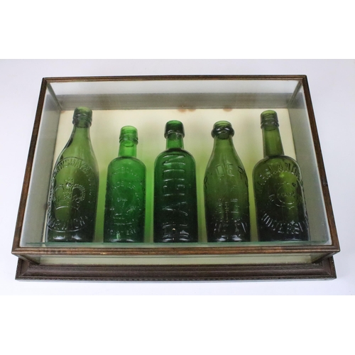 162 - Five 20th century green glass beer bottles in wood and glass display case H 36cm W 51cm D 11cm