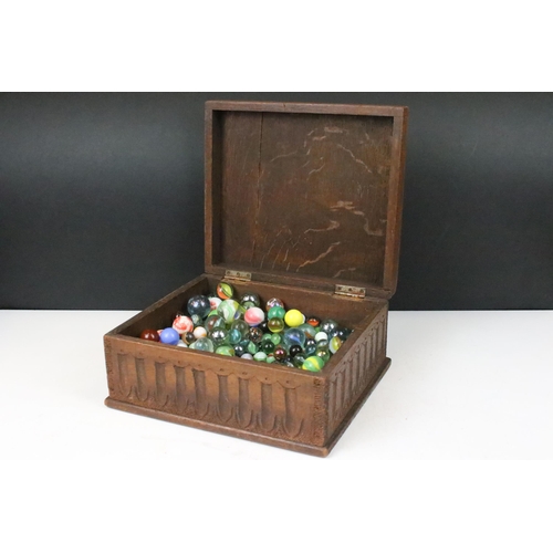 174 - Oak carved wooden box containing a large collection of glass marbles, box measures 15cm wide