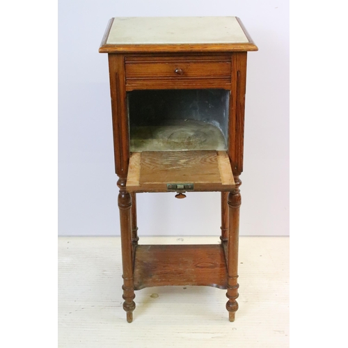 592 - Early 20th century pine bedside pot stand, the inset marble top above single drawer and fall front c... 