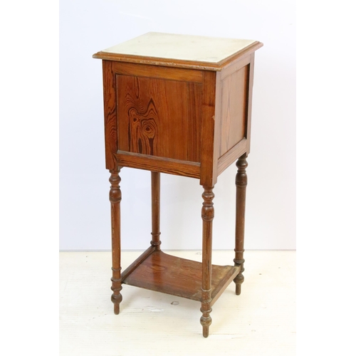 592 - Early 20th century pine bedside pot stand, the inset marble top above single drawer and fall front c... 