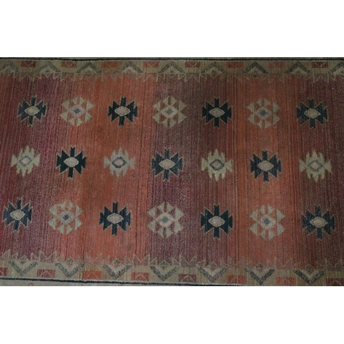 578 - Terracotta ground woollen rug with geometric central design and borders, 232 x 160cm