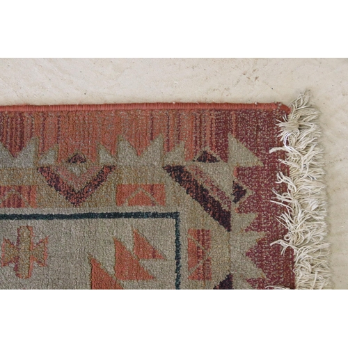 578 - Terracotta ground woollen rug with geometric central design and borders, 232 x 160cm