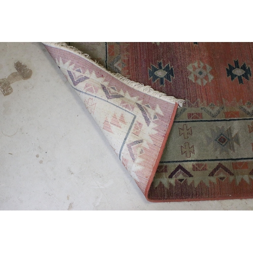 578 - Terracotta ground woollen rug with geometric central design and borders, 232 x 160cm