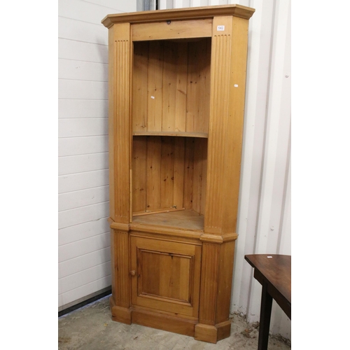 643 - 20th century pine corner cupboard, the upper section with two open shelves above single cupboard doo... 