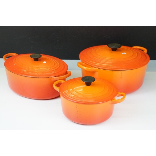 127 - Three Le Creuset lidded orange pans in graduating sizes, two round, 18 & 26 and one oval example BC,... 