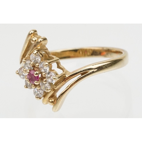 159 - 9ct gold cubic zirconia and ruby crossover ring having a round cut ruby to entre surrounded by round... 