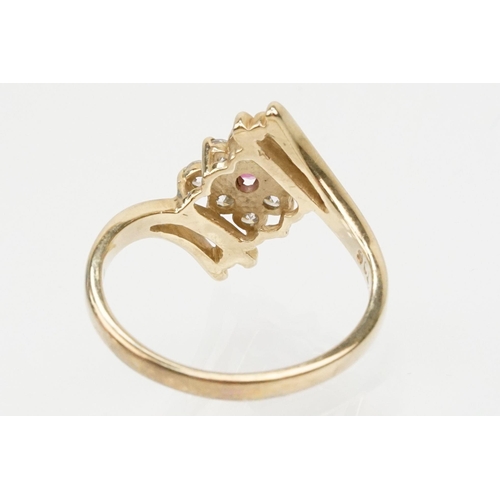 159 - 9ct gold cubic zirconia and ruby crossover ring having a round cut ruby to entre surrounded by round... 