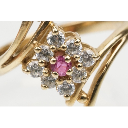 159 - 9ct gold cubic zirconia and ruby crossover ring having a round cut ruby to entre surrounded by round... 