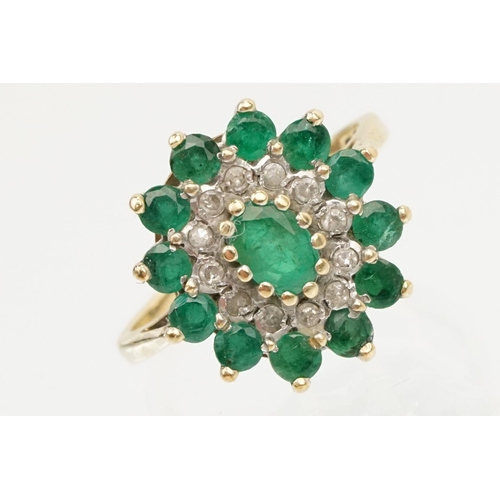 21 - 9ct gold, emerald and diamond cluster ring. The ring being set with a central oval cut emerald surro... 