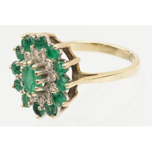 21 - 9ct gold, emerald and diamond cluster ring. The ring being set with a central oval cut emerald surro... 