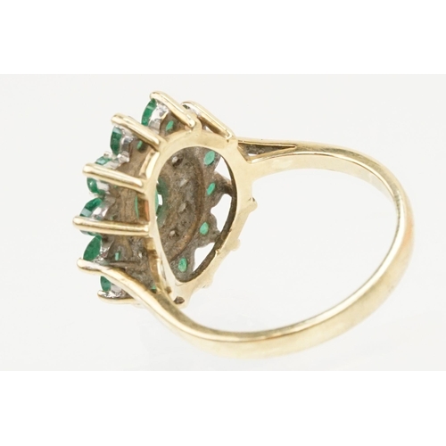 21 - 9ct gold, emerald and diamond cluster ring. The ring being set with a central oval cut emerald surro... 