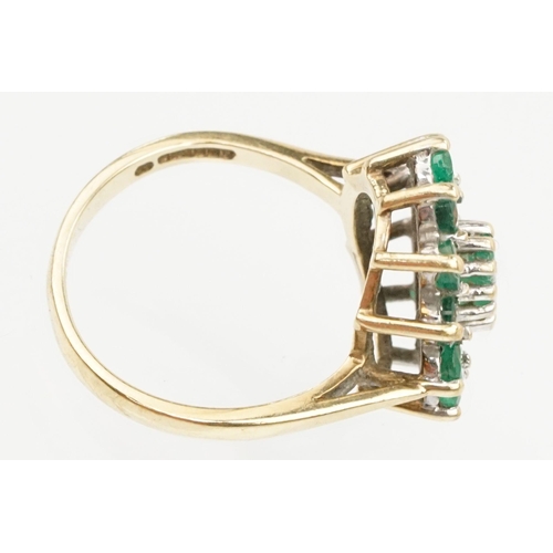 21 - 9ct gold, emerald and diamond cluster ring. The ring being set with a central oval cut emerald surro... 