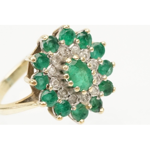 21 - 9ct gold, emerald and diamond cluster ring. The ring being set with a central oval cut emerald surro... 