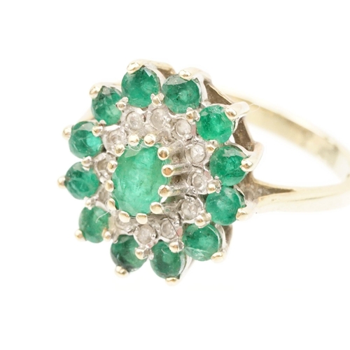 21 - 9ct gold, emerald and diamond cluster ring. The ring being set with a central oval cut emerald surro... 