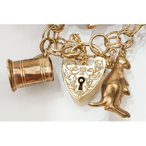 215 - 9ct gold double link bracelet with heart padlock clasp, having 21 charms. 19 charms marked 9ct or ha... 