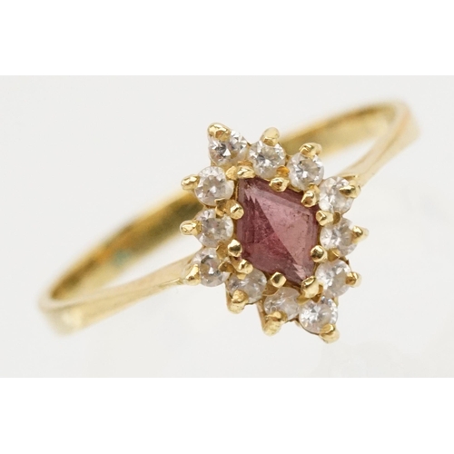 223 - 18ct gold ruby and cz ring. The ring being set with a step cut ruby with a halo of round cut cz's. B... 