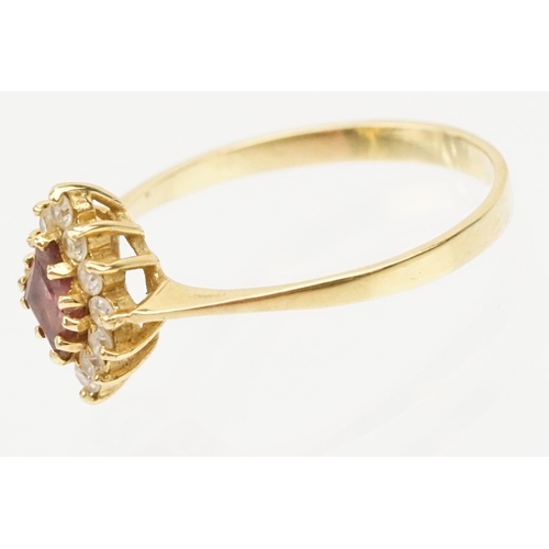 223 - 18ct gold ruby and cz ring. The ring being set with a step cut ruby with a halo of round cut cz's. B... 