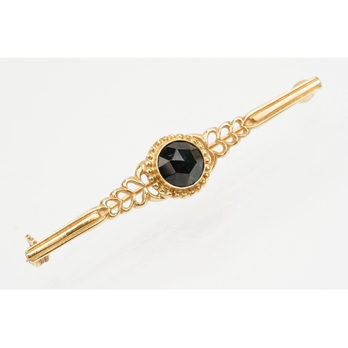 236 - Two 20th Century brooches to include a 14ct gold and garnet bar brooch set with a faceted garnet to ... 