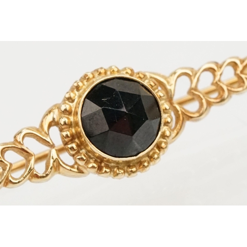 236 - Two 20th Century brooches to include a 14ct gold and garnet bar brooch set with a faceted garnet to ... 