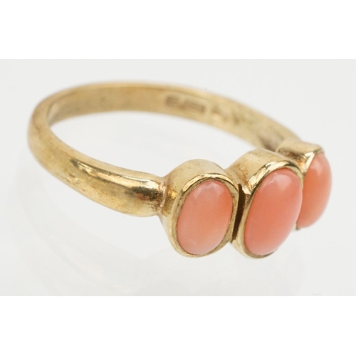 242 - 9ct gold and coral three stone ring. The ring being set with three coral cabochons in bezel settings... 