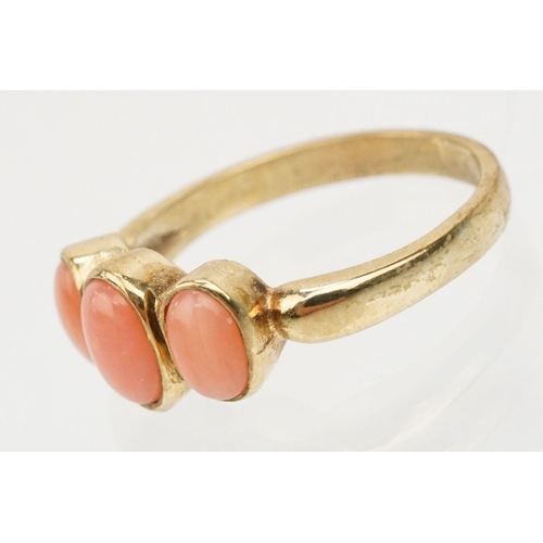 242 - 9ct gold and coral three stone ring. The ring being set with three coral cabochons in bezel settings... 