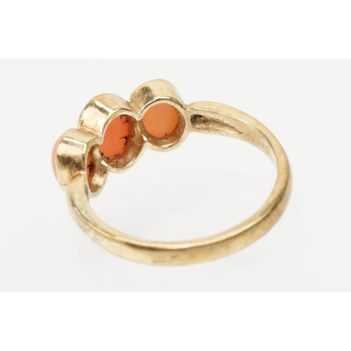 242 - 9ct gold and coral three stone ring. The ring being set with three coral cabochons in bezel settings... 