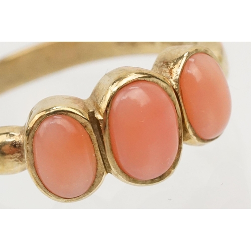 242 - 9ct gold and coral three stone ring. The ring being set with three coral cabochons in bezel settings... 