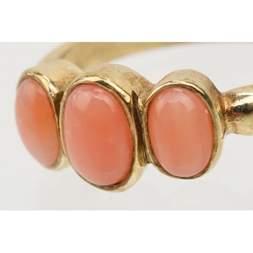 242 - 9ct gold and coral three stone ring. The ring being set with three coral cabochons in bezel settings... 