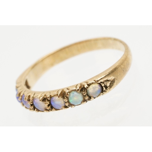 243 - Opal seven stone ring set with seven round opal cabochons. Marks rubbed, tests indicate 9ct gold. Si... 